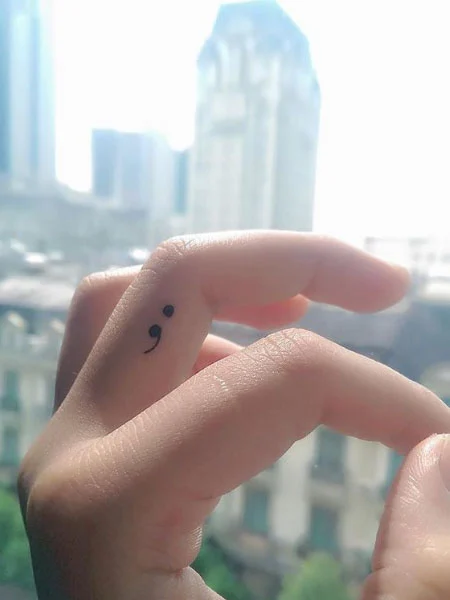 Tatuaje de punto y coma en el dedo