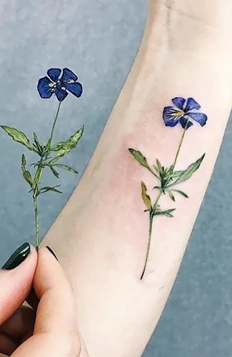 tatuaje de flor violeta en el ante brazo